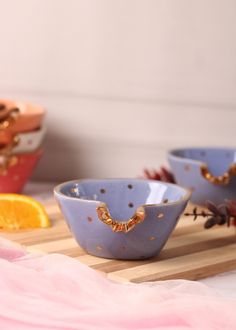 three blue bowls sitting on top of a wooden cutting board next to an orange slice