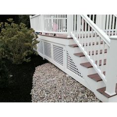 a white stair case next to some bushes and rocks on the side of a house