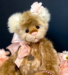 a brown teddy bear with pink flowers on its head sitting in front of a blue background