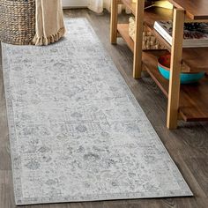 a large rug in the middle of a living room with wooden floors and white walls