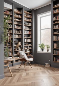 an empty room with bookshelves and a chair in front of a window filled with plants