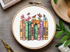 a cross stitch pattern with books and flowers on it, sitting next to some other items