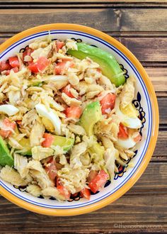 a bowl filled with pasta salad on top of a wooden table