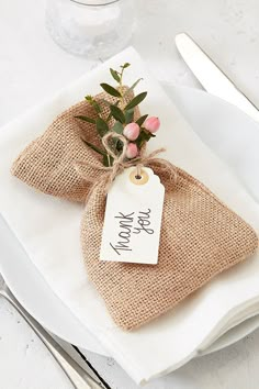 a place setting with burlap bags and flowers