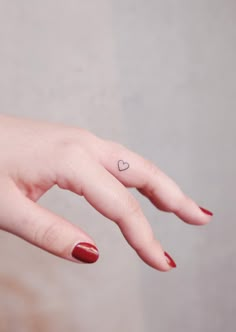 a woman's hand with a small heart tattoo on her left thumb and finger