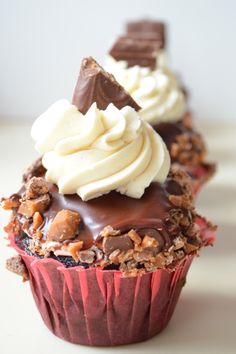 three cupcakes with chocolate frosting and nuts on top