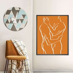 an orange and white painting hangs on the wall next to a chair