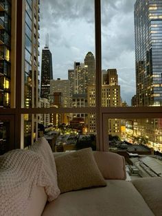 a couch sitting in front of a window next to a cityscape at night