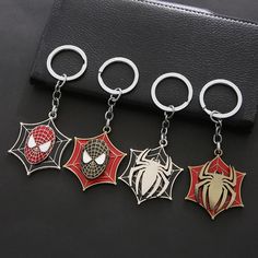 four spider - man keychains are shown on a black surface