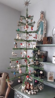 a small christmas tree with ornaments on it in a living room next to a shelf