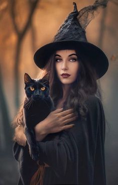 a woman dressed as a witch holding a black cat