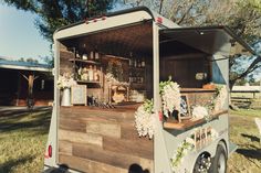 an old fashioned food truck is decorated with flowers and greenery