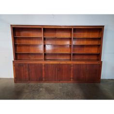 a wooden bookcase with two doors and three shelves on one side, against a white wall