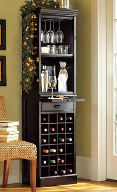 a wine rack with bottles and glasses on it in front of a chair next to a christmas tree