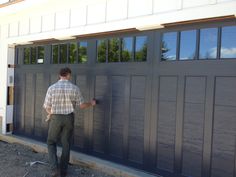 a man in plaid shirt and khaki pants standing next to a garage door