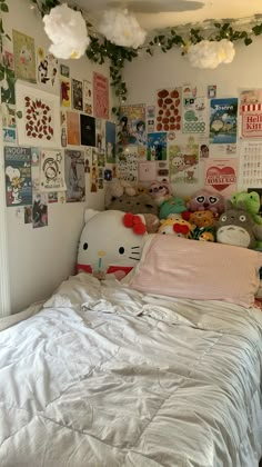 there is a bed with many pictures on the wall above it and a hello kitty stuffed animal