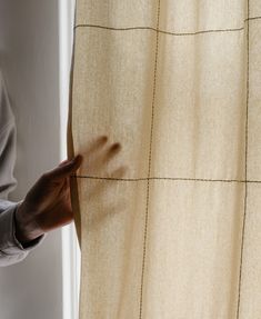 a person is opening the curtain with their hand