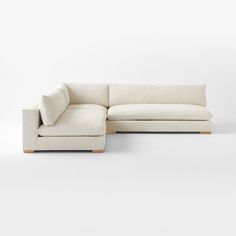 a white sectional couch with pillows on the top and bottom, sitting in front of a white background