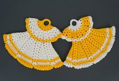 two yellow and white crocheted bibs on a gray surface, one is holding the other