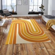 an orange and white rug in a living room with wood flooring, windows, and furniture