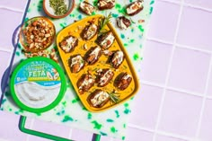 an assortment of food on a table with green sprinkles and white tiles