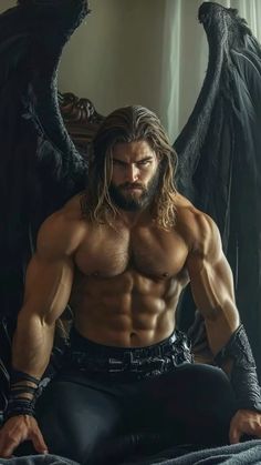 a man with long hair sitting on top of a bed next to black angel wings