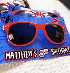 red sunglasses with spiderman stickers on them are sitting on a blue birthday card