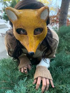 a woman wearing a fox mask in the grass