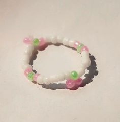 two white bracelets with pink and green beads