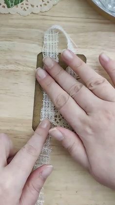 two hands are working on a piece of lace