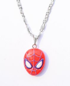 a spiderman necklace is shown on a white surface with chain attached to the clasp