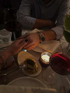 two people sitting at a table with wine and food