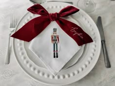 a white plate topped with a red bow and a nutcracker napkin on top of it