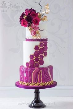 a three tiered cake with purple and gold decorations on it's top layer