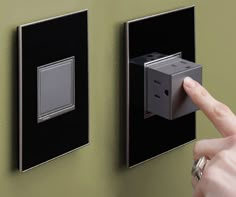 a person is pressing the button on a wall outlet with an electrical outlet attached to it