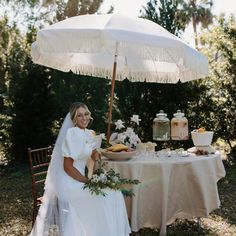 a woman sitting at a table with an umbrella