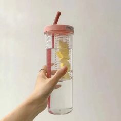 a person holding a glass with lemon slices in it and a straw sticking out of the top