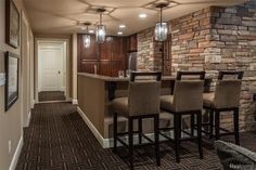 a room with a bar and some chairs in it, next to a brick wall