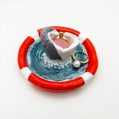 a ring sits on top of a small bowl with a shark in it's mouth