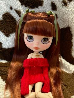 a doll with long red hair wearing a red sweater