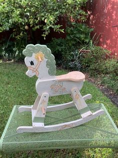 a wooden rocking horse sitting in the grass