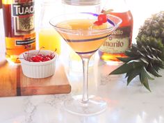 a pineapple martini is garnished with cherries