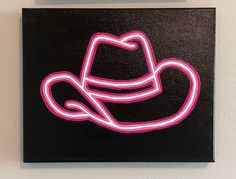 a black square with a pink neon cowboy hat on it