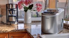 a coffee maker sitting on top of a kitchen counter next to a vase with flowers