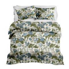 a bed with blue and green flowers on the comforter, along with two pillows