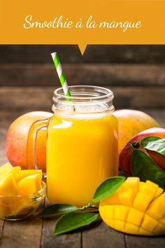 there is a mango smoothie in a mason jar next to some fruit on the table