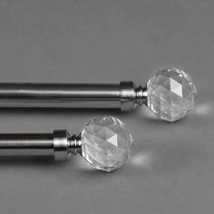 two crystal knobs with black handles on a gray surface, next to each other