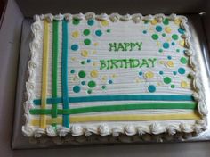 a birthday cake with white frosting and green, yellow and blue decorations on it