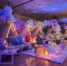 a room filled with lots of balloons and lights on the ceiling, next to a couch