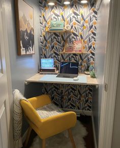 a laptop computer sitting on top of a desk in front of a wallpapered wall